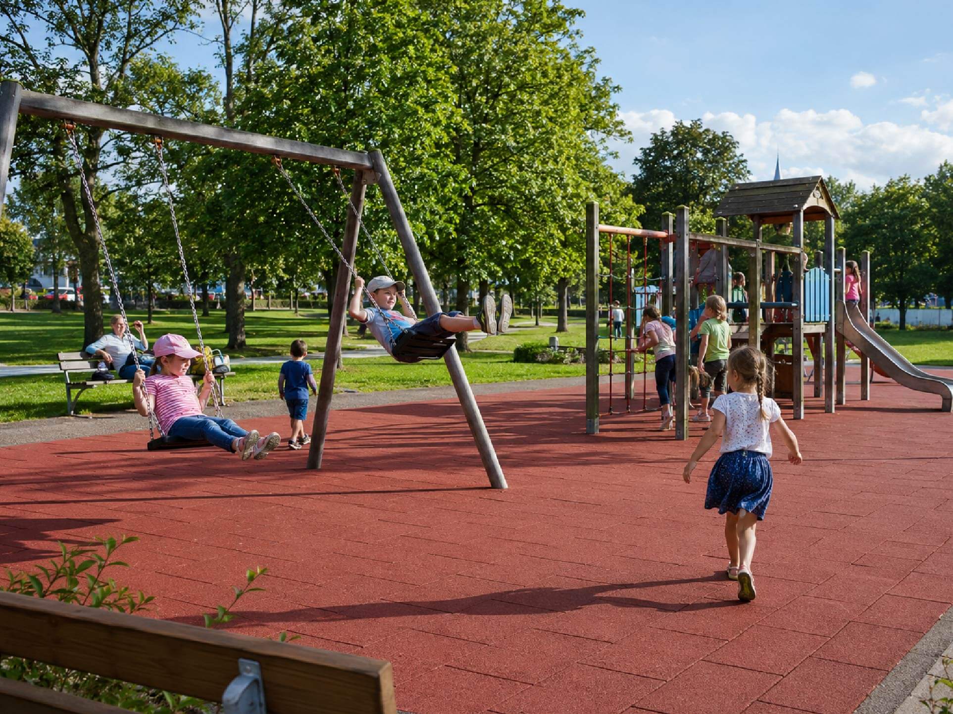 Spielende Kinder auf dem Spielplatz mit Fallschutzplatten